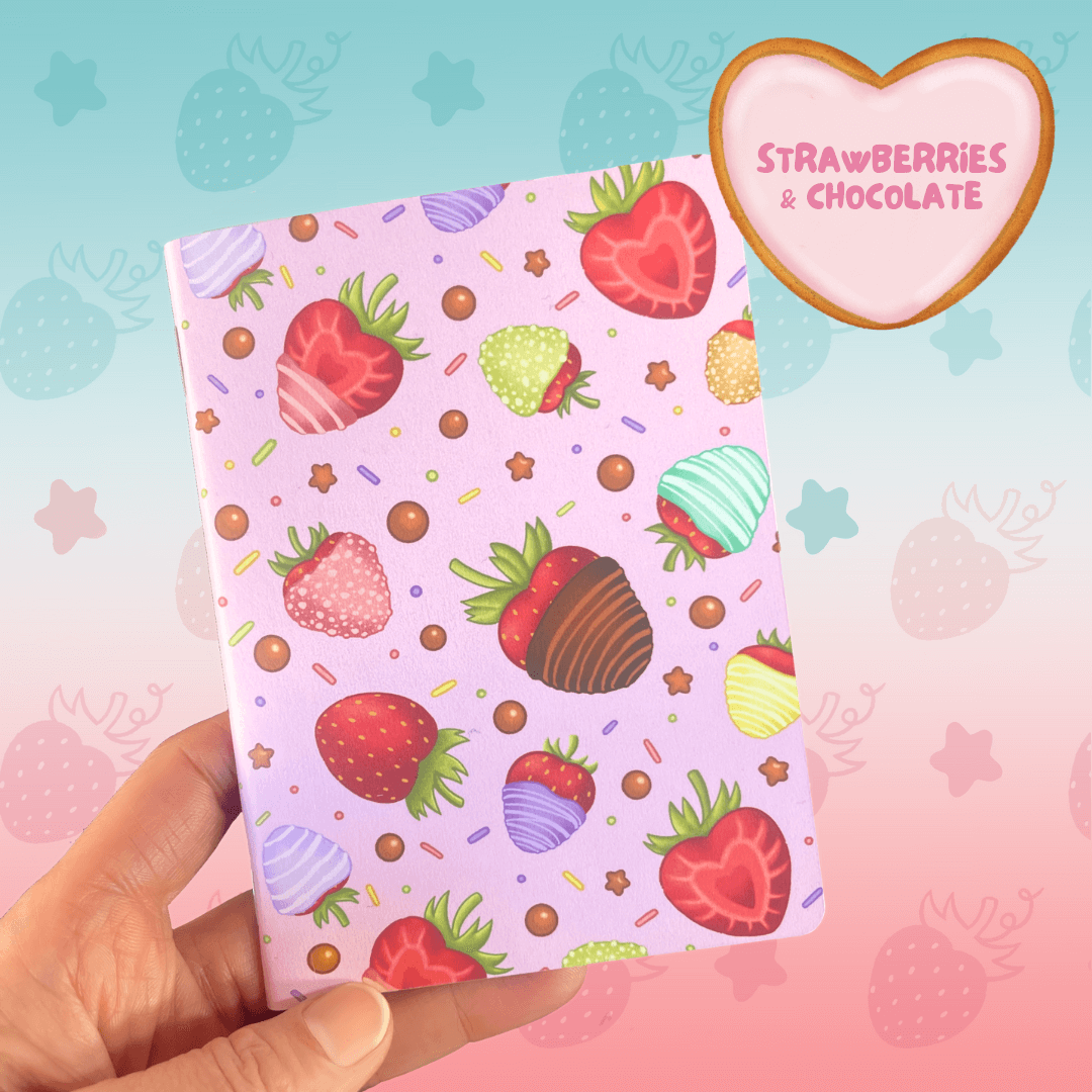 An A6 notebook with strawberries & Chocolate pattern with a pink background.